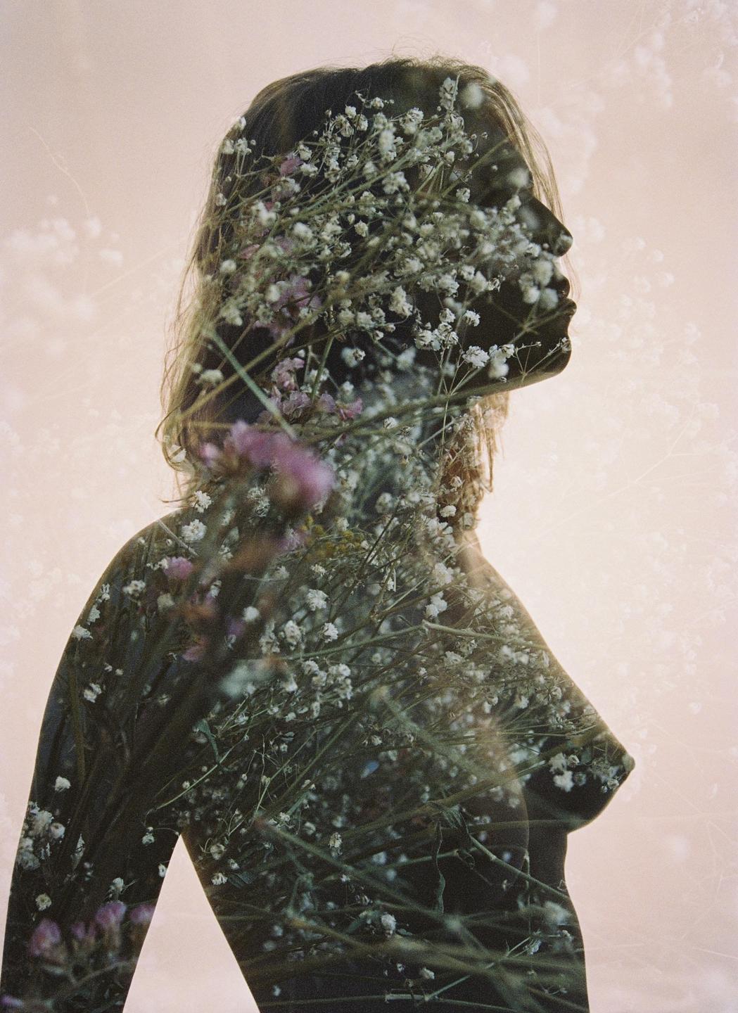 A double exposure shows a woman's profile filled with small white and purple flowers.