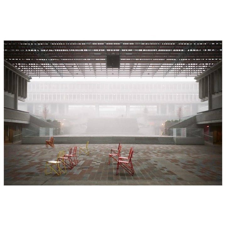 A courtyard with several colorful chairs is visible through a thick fog.