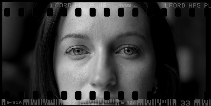 A woman's face is visible through a film strip.