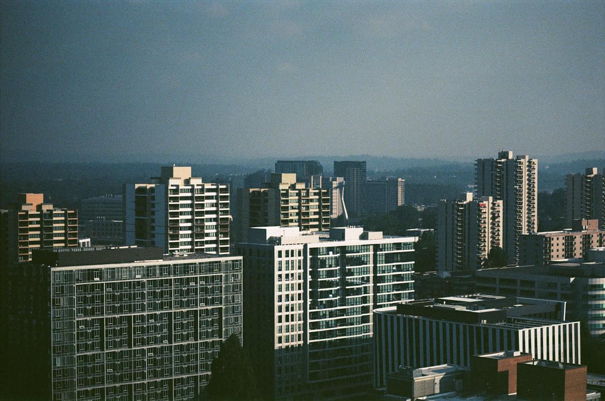 A city skyline with numerous tall buildings under a hazy sky.