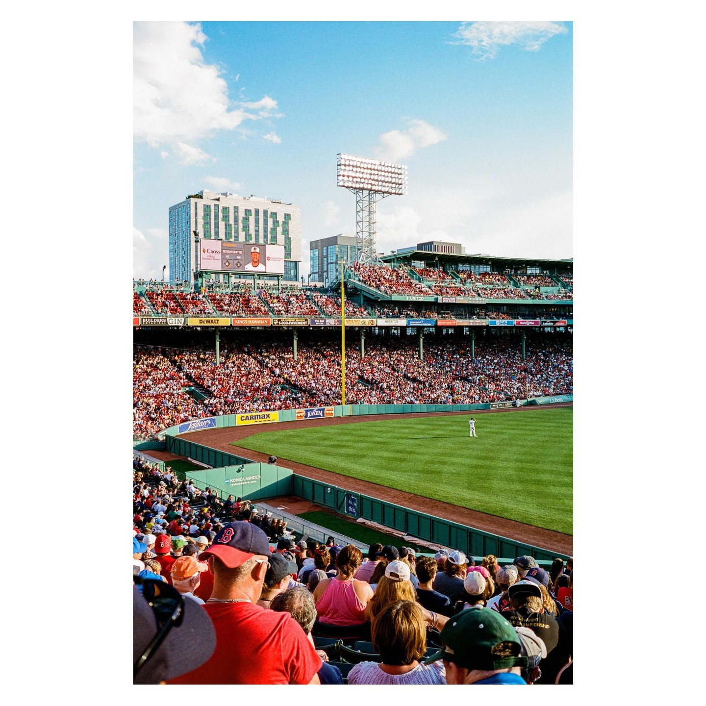 A baseball stadium is filled with spectators watching a game on a sunny day.
