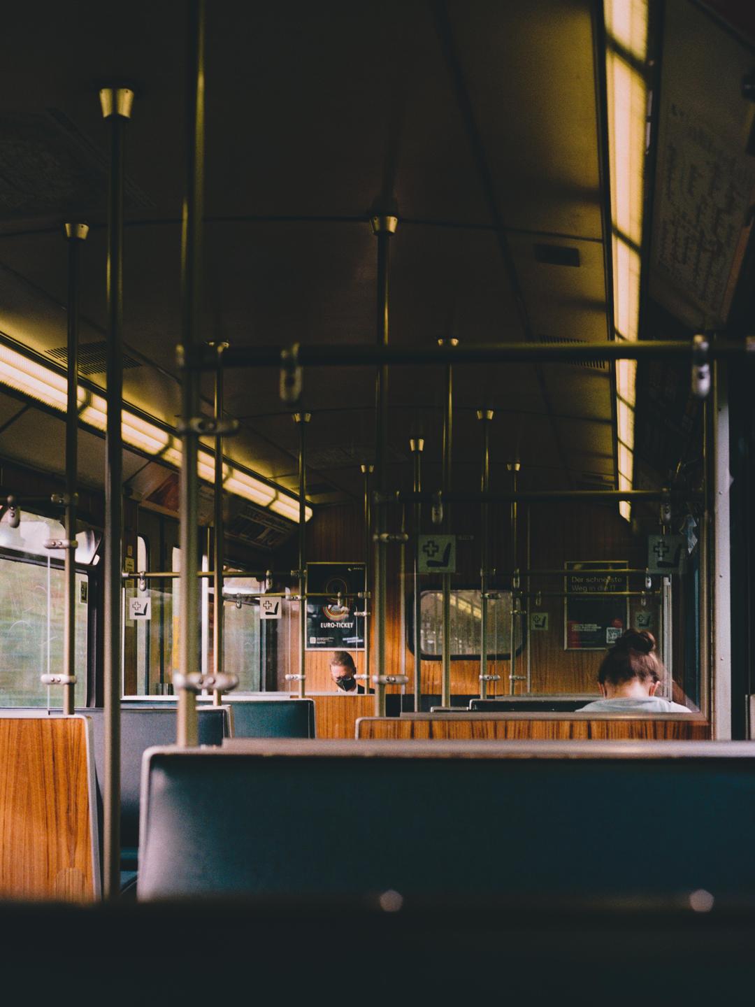 The interior of a subway car is visible with two passengers and warm lighting.