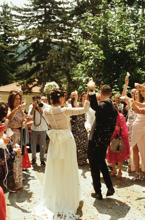 A newlywed couple walks through a shower of confetti and rice as guests celebrate their wedding.