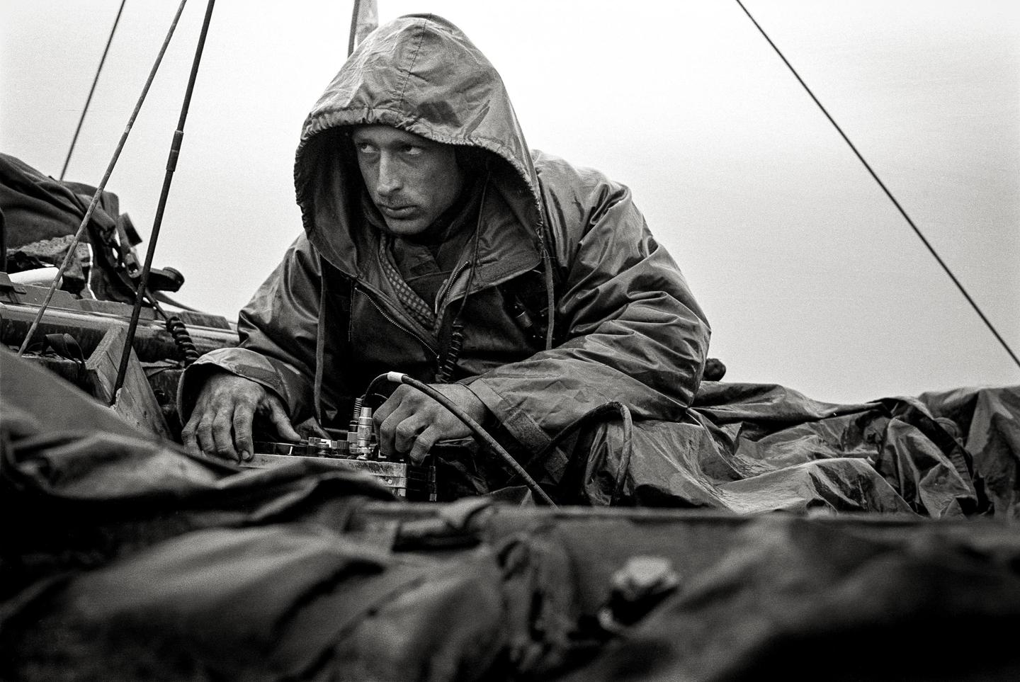 A man in a hooded jacket operates equipment with his hands.