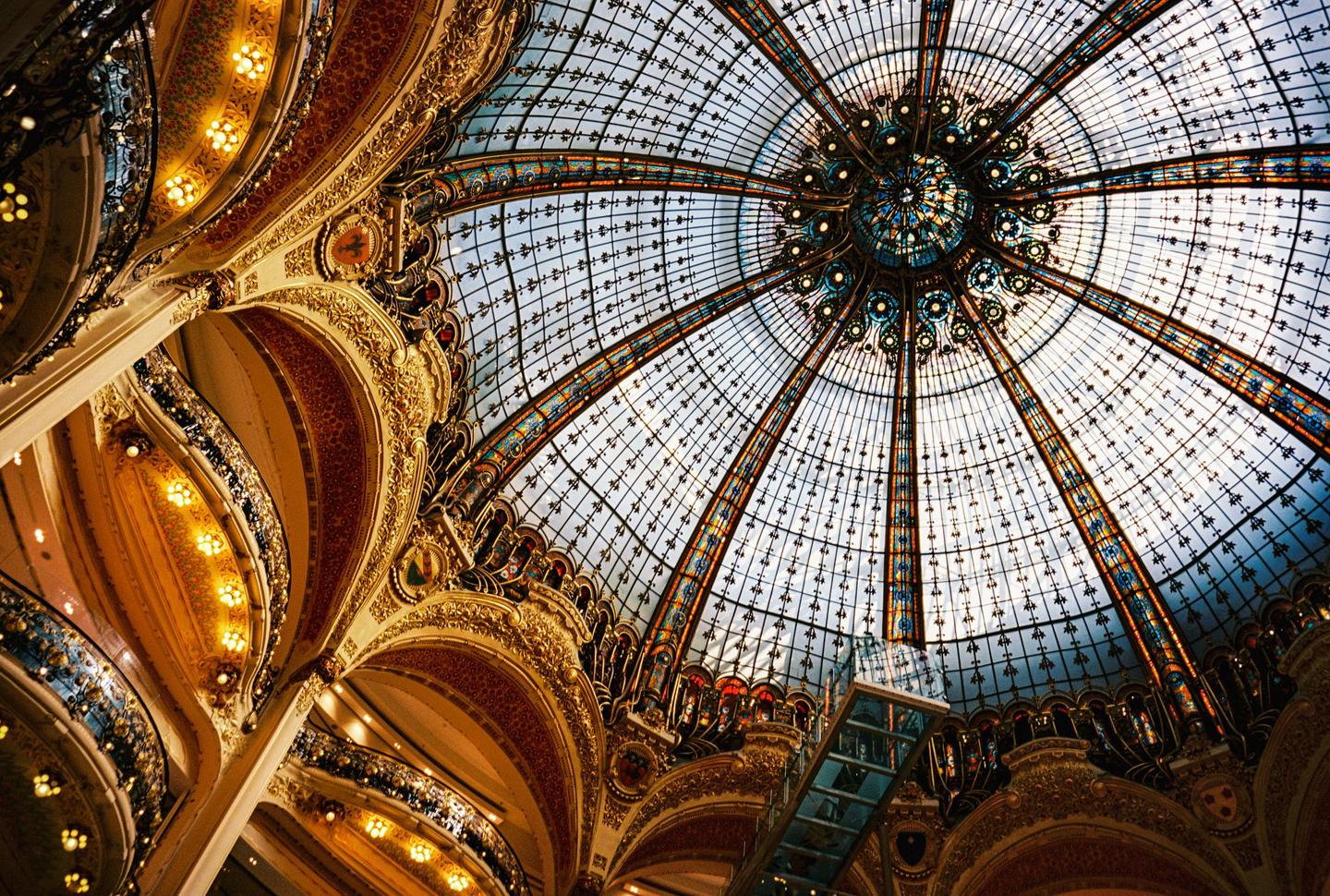 A low-angle view shows the ornate interior of a building with a large stained-glass dome.