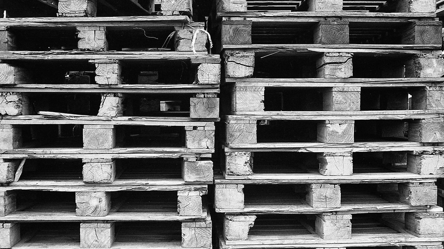 Two stacks of wooden pallets are shown in a close-up, filling the frame.