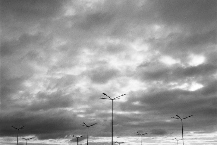 Several streetlights are silhouetted against a cloudy sky.