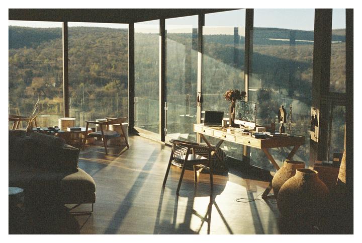 Sunlight streams into a modern room with large windows overlooking a wooded landscape.