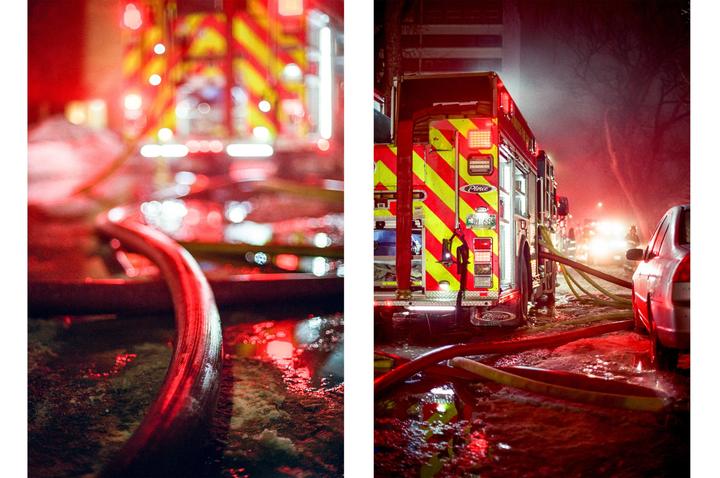A fire truck with hoses on the ground is illuminated by red lights at night.