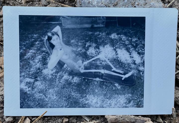 A woman with a skeleton body is lying on a lounge chair in a double exposure self-portrait.