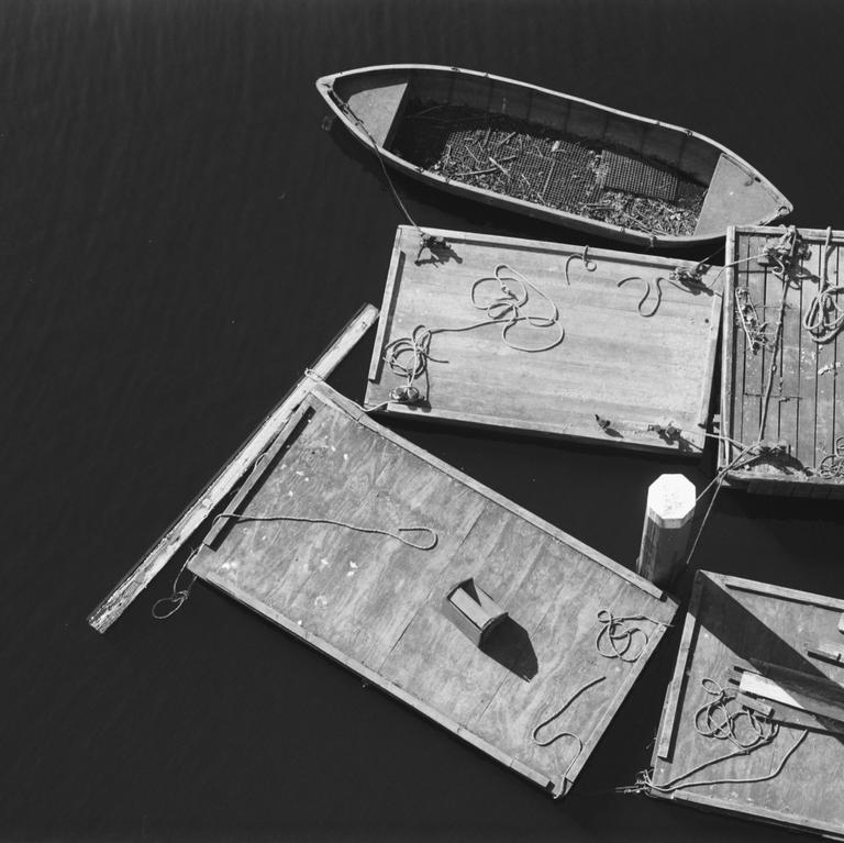 A small boat is tied to a wooden dock floating on dark water.