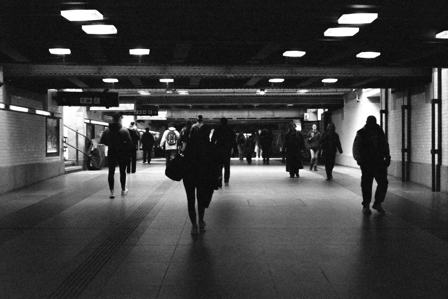 People walk through a dimly lit underground passage.