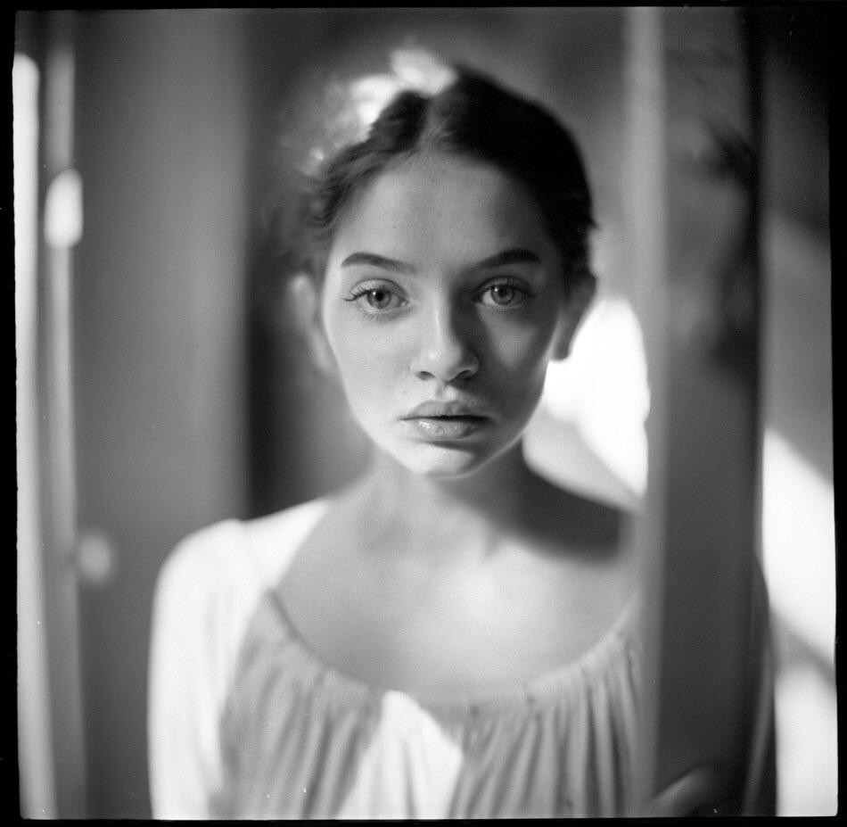 A woman with dark hair pulled back looks directly at the viewer.