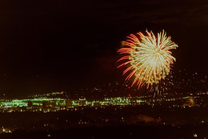 A large firework explodes over a city at night.