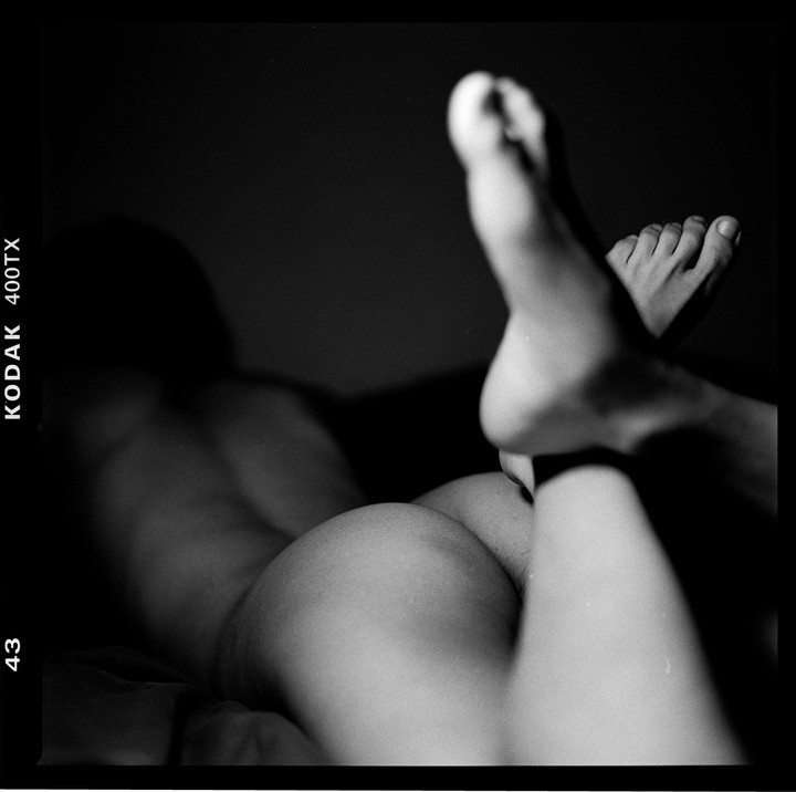 A person is lying on their stomach with their legs crossed and feet in the air.