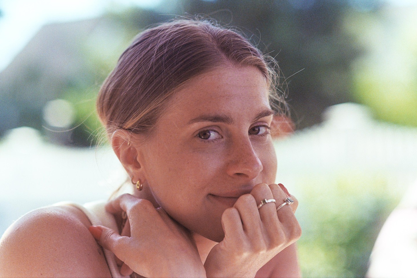 A woman with light brown hair and rings on her fingers looks directly at the viewer.