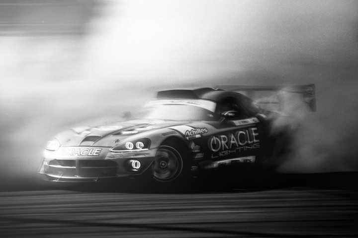 A race car drifts on a track, surrounded by smoke.