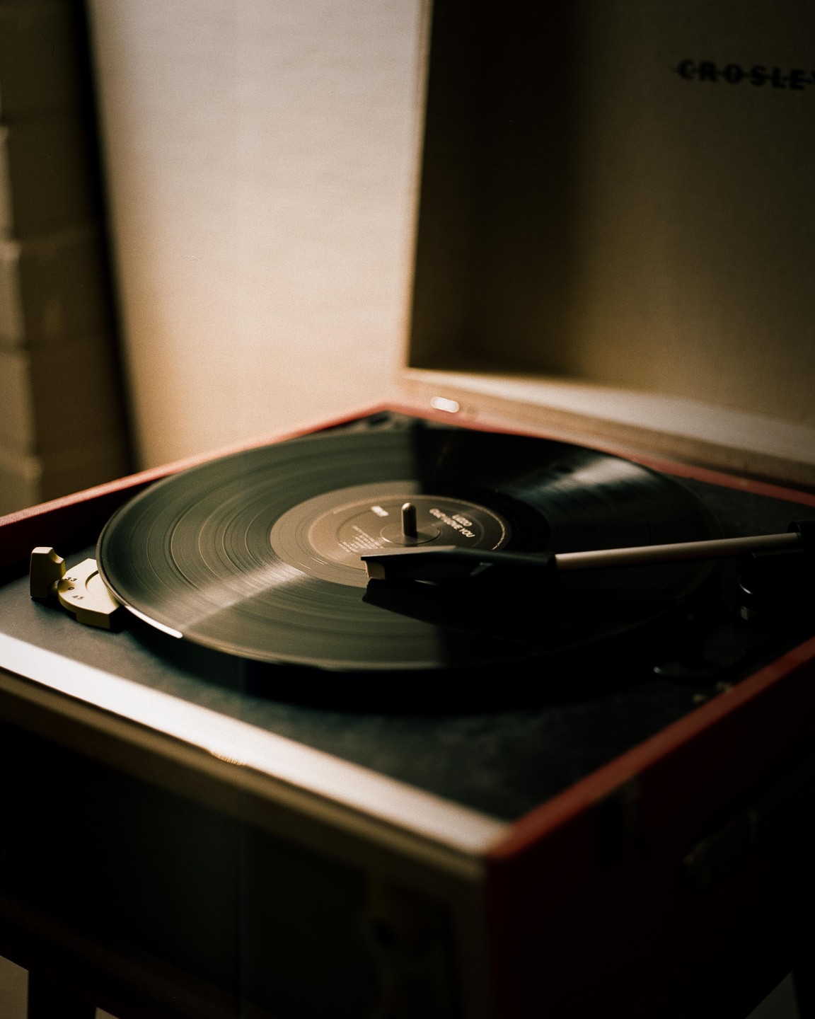 A record player with a vinyl record on its turntable is shown in a close-up shot.