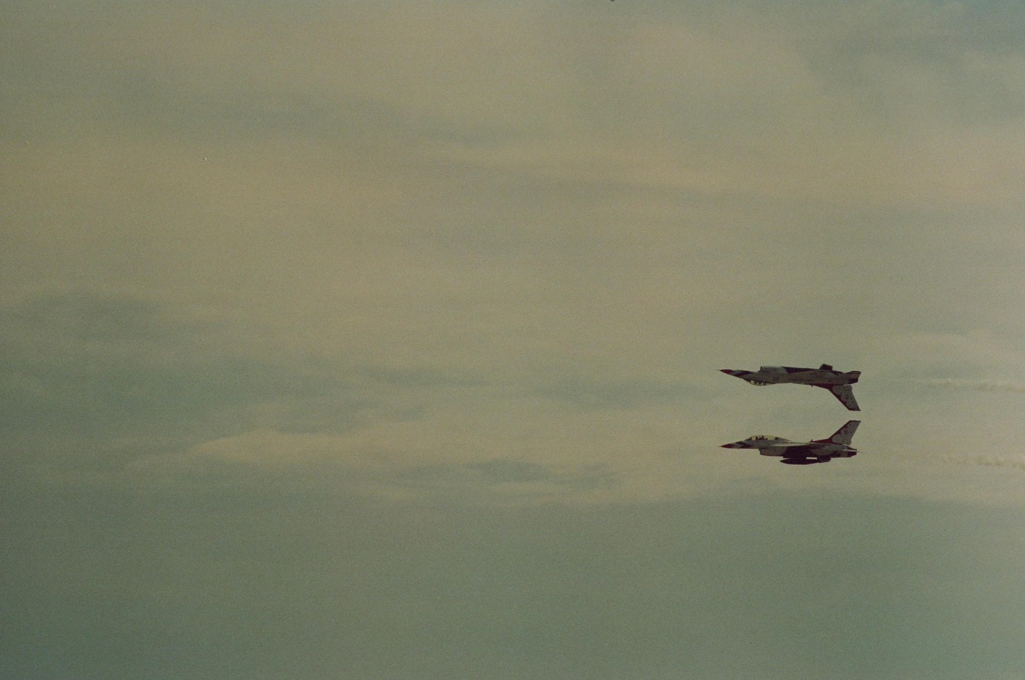 Two fighter jets fly in formation against a cloudy sky.