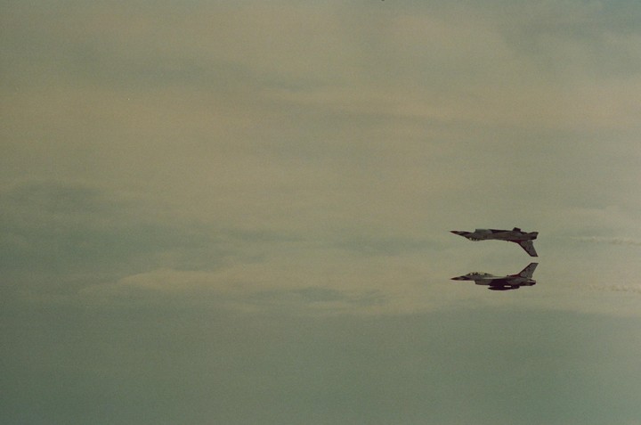 Two fighter jets fly in formation against a cloudy sky.