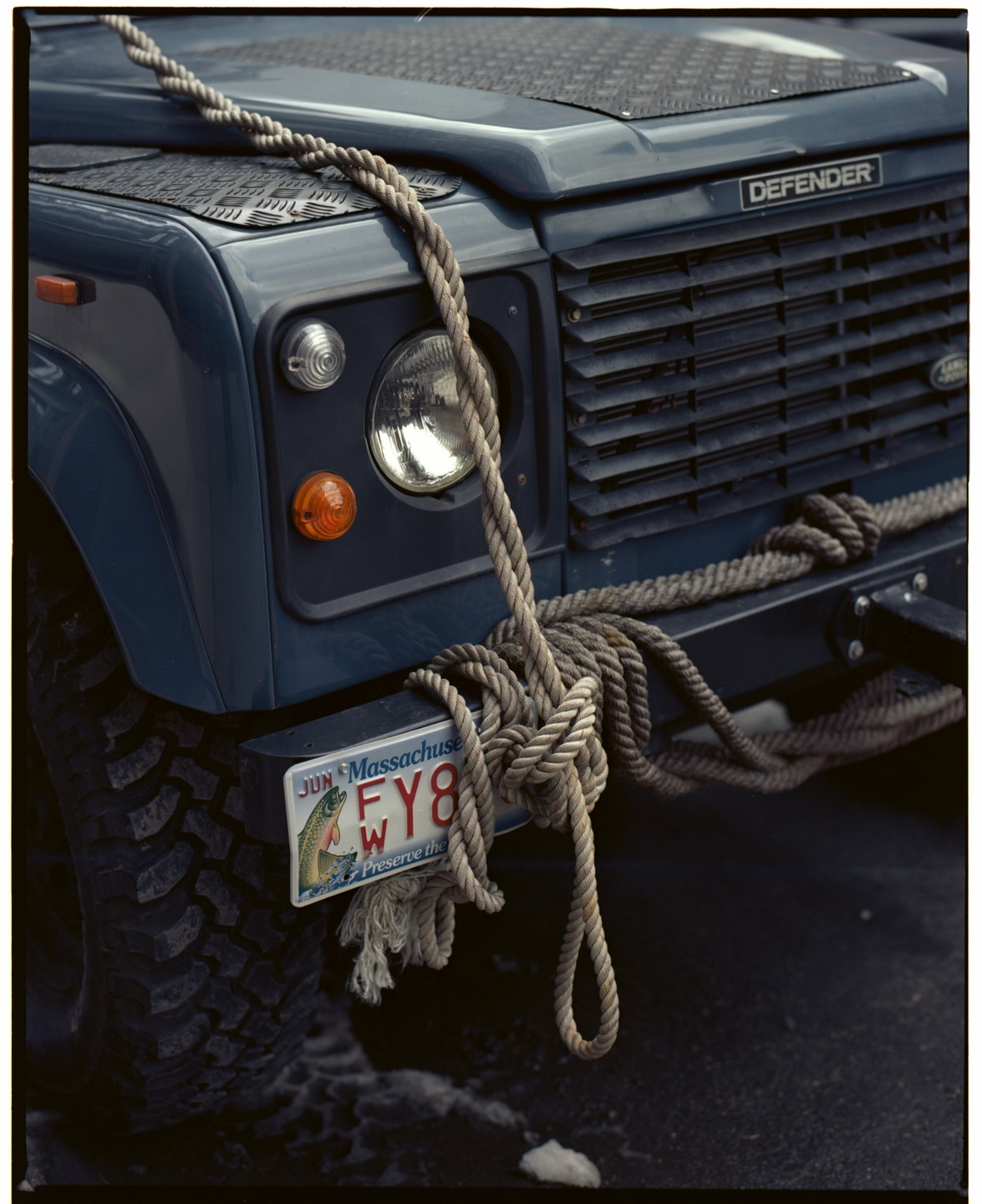 A thick rope is draped over the front of a blue Land Rover Defender.