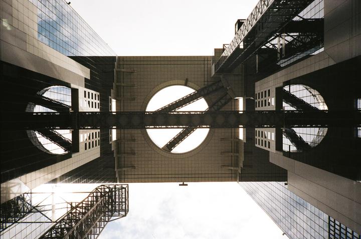 A low-angle view shows the Umeda Sky Building with its two towers connected by bridges and a circular observation deck.