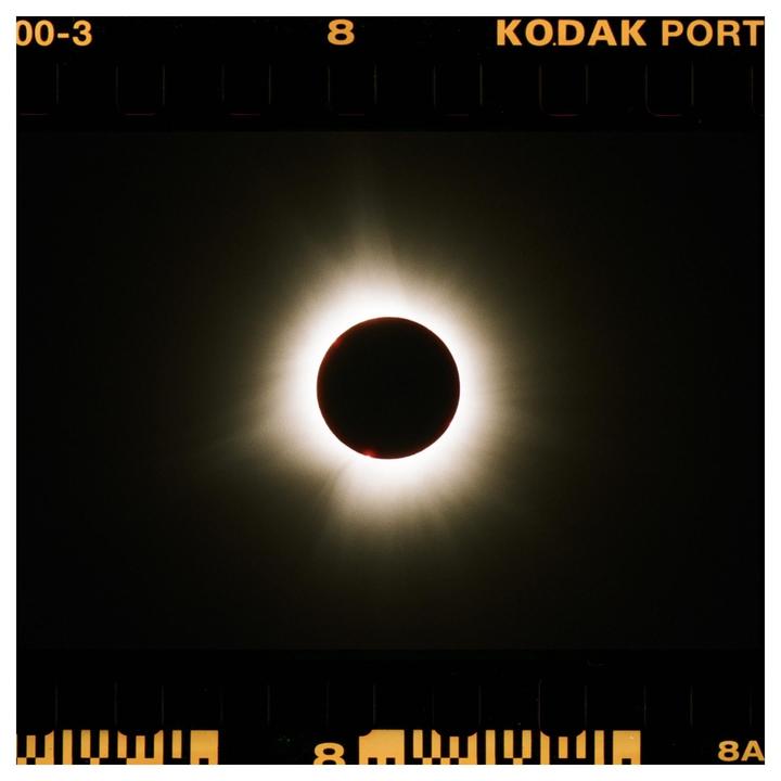 A total solar eclipse is visible with a bright corona around the moon.