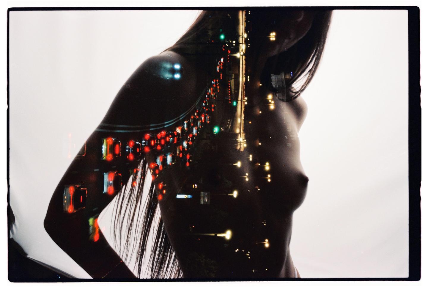 A double exposure shows a woman's torso overlaid with a street scene at night.
