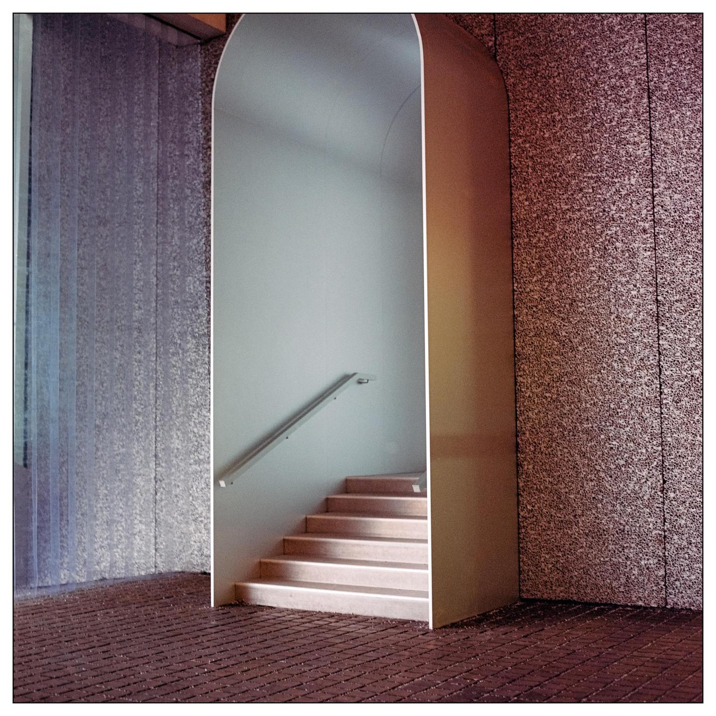 A light-colored staircase with a handrail is visible through an arched doorway.