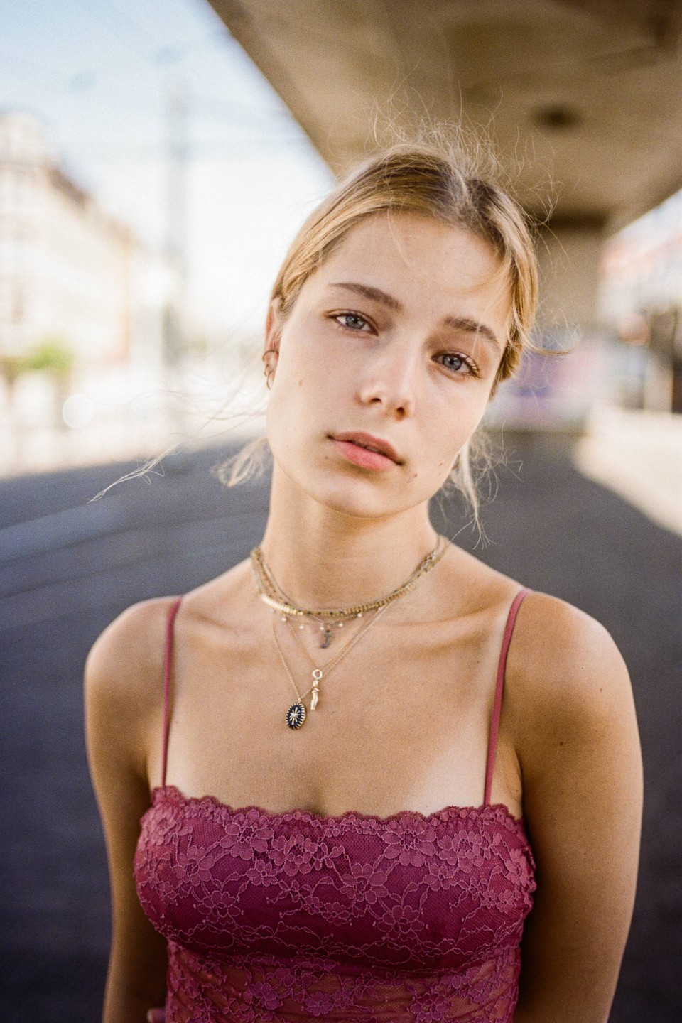 A woman with blonde hair and a lace top looks directly at the viewer.