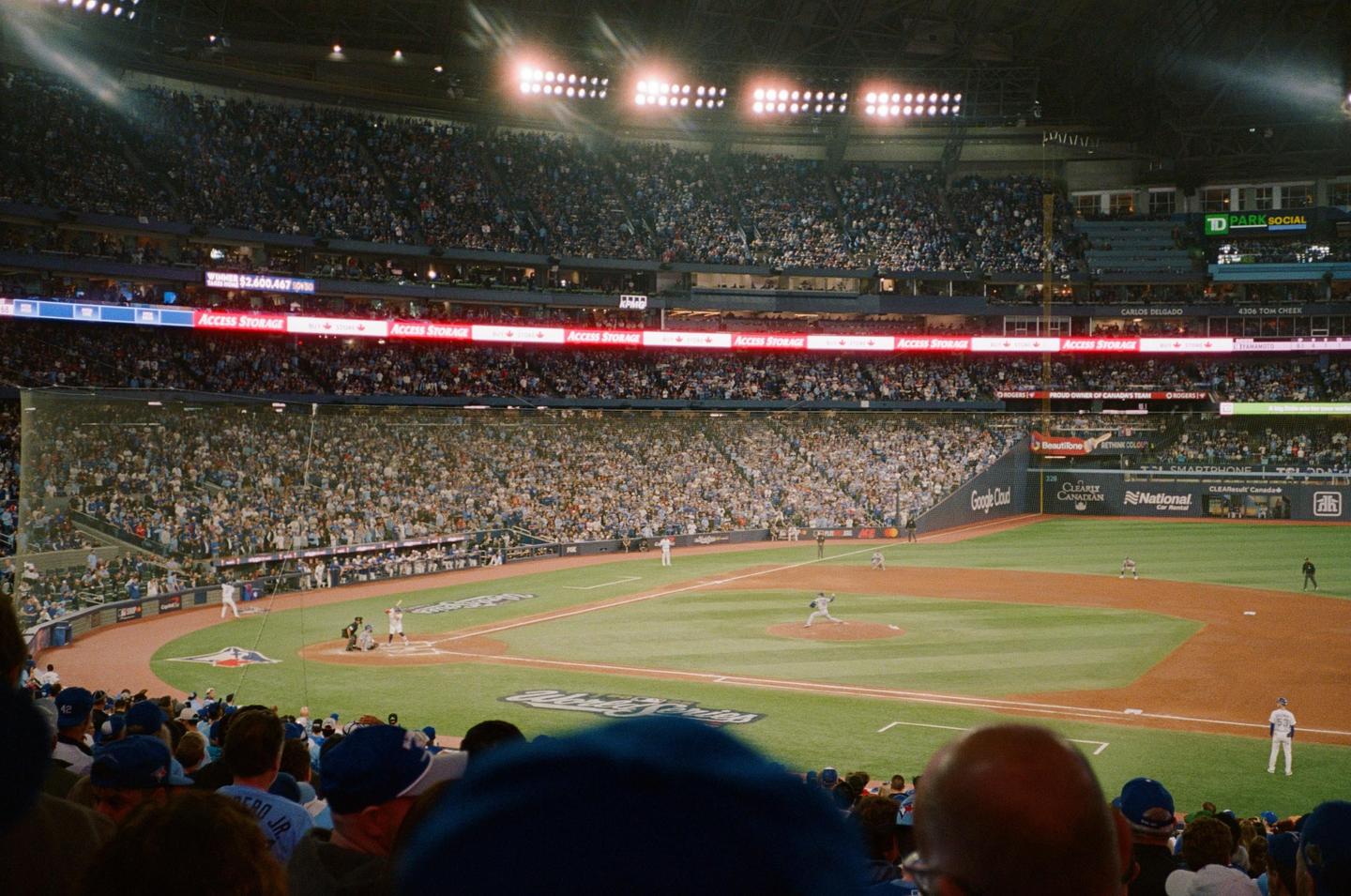 A baseball game is in progress at a stadium filled with spectators under bright lights.