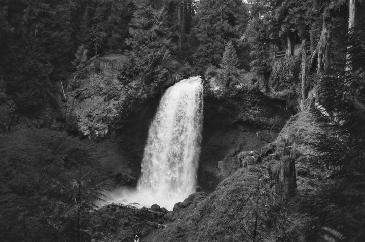 A powerful waterfall cascades into a pool surrounded by lush forest.