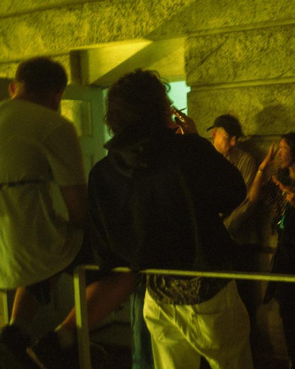 A group of people are gathered at night, illuminated by a green light.