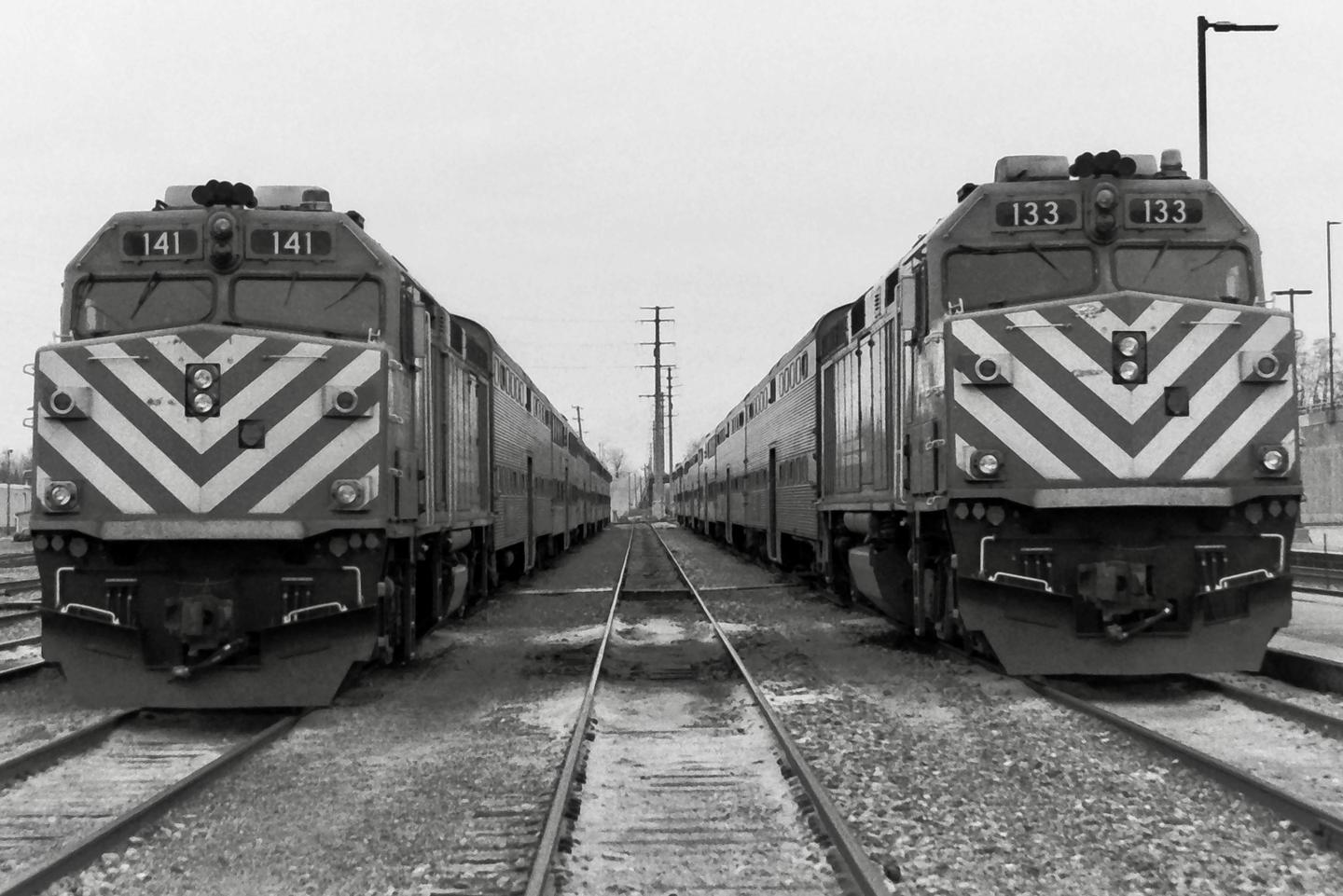 Two trains face each other on parallel tracks, with power lines visible in the distance.