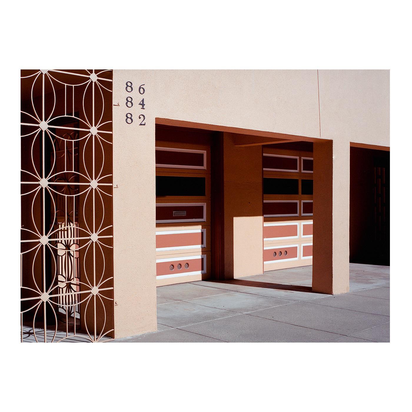 A building with three garage doors and a decorative metal gate is shown from a low angle.
