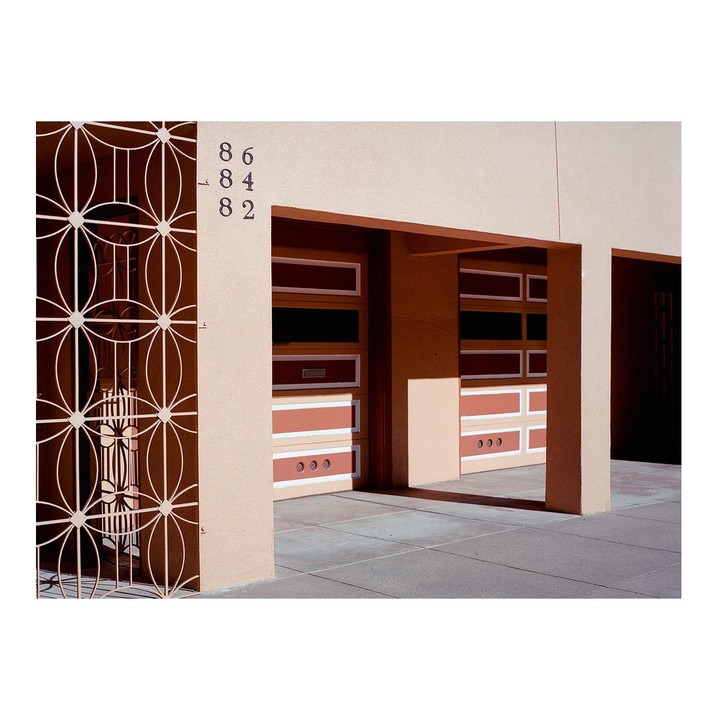 A building with three garage doors and a decorative metal gate is shown from a low angle.