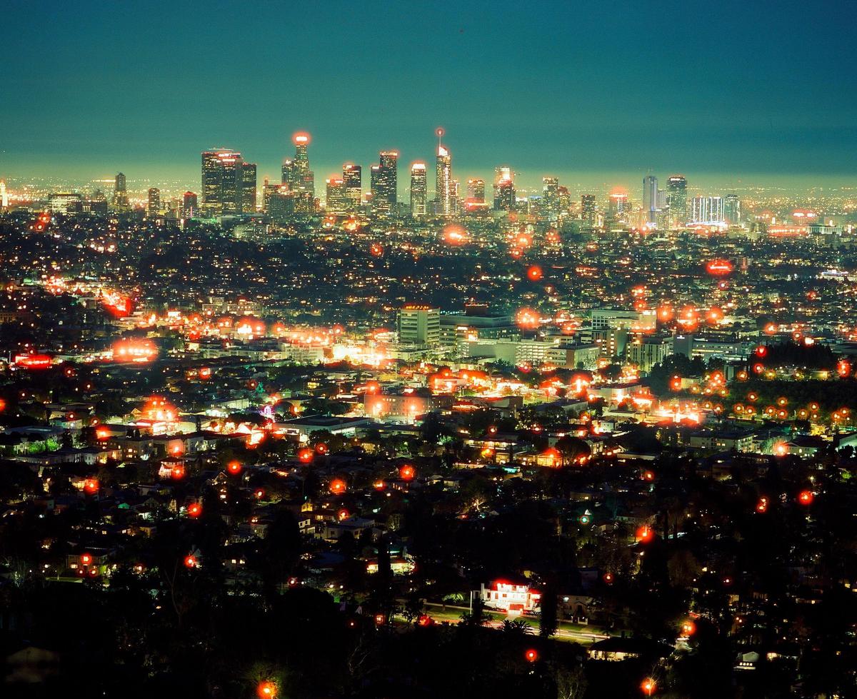 A panoramic view of the Los Angeles skyline at night, with city lights stretching into the distance.