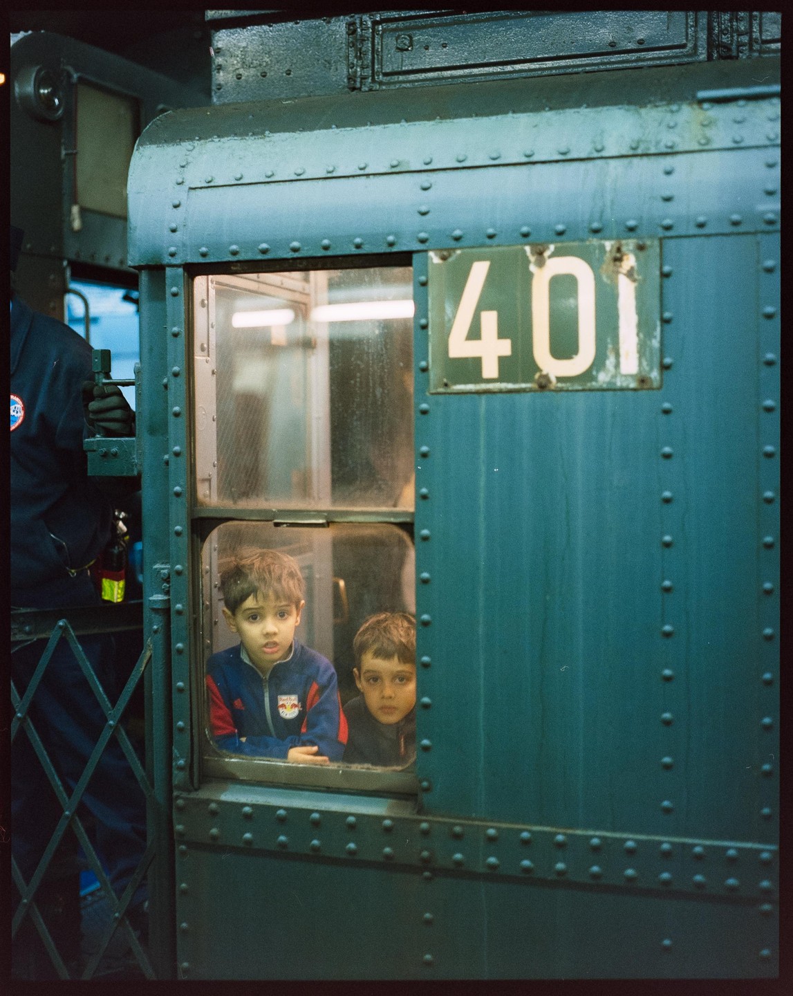 Two boys look out of a window on a green train car with the number 401.