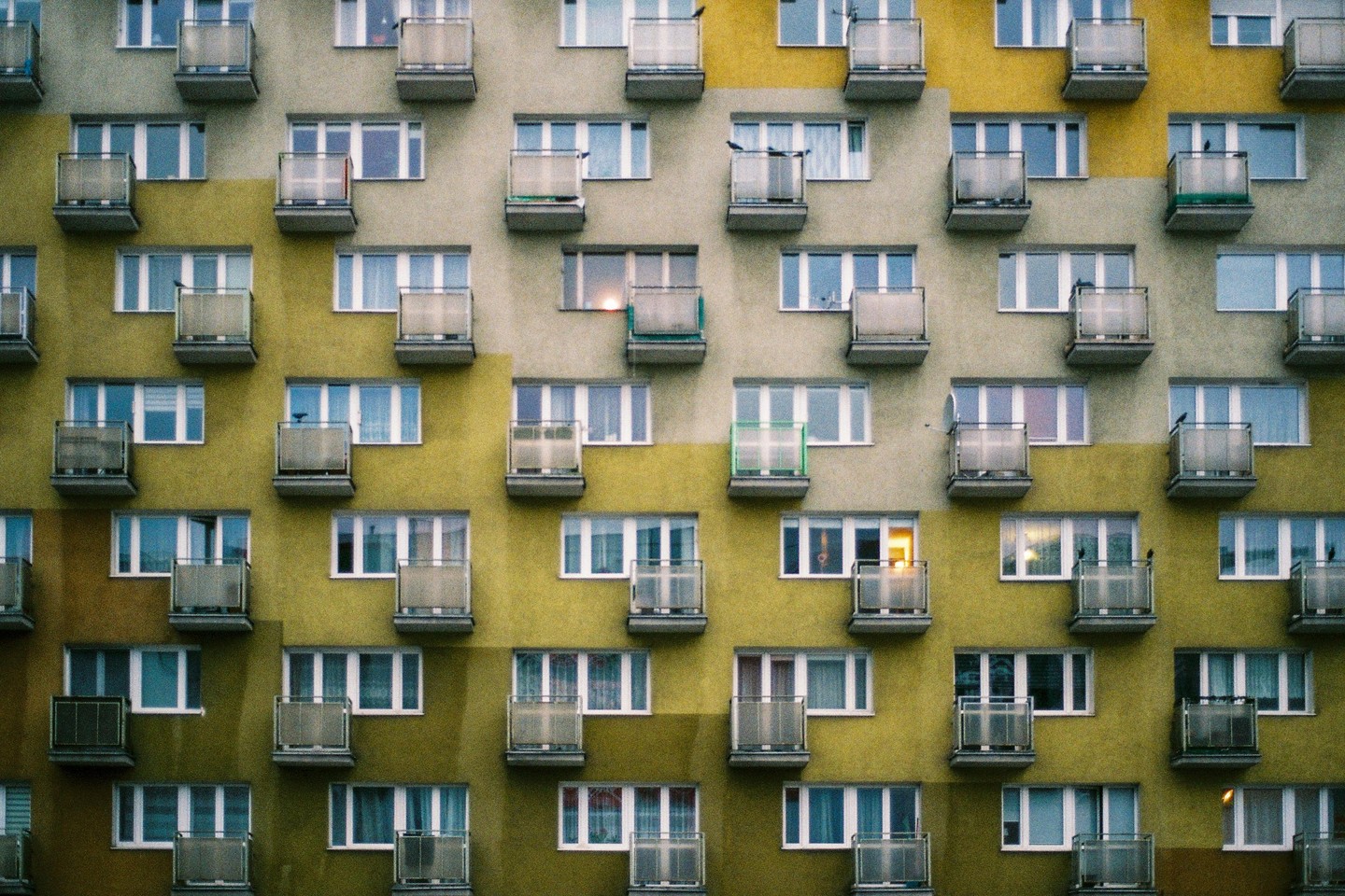 The facade of a building is covered in windows and balconies, with some windows showing light from inside.