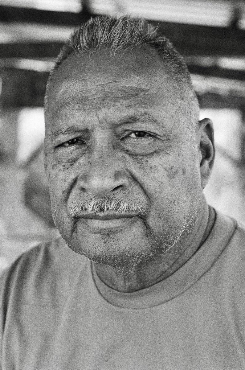 A man with a mustache and short hair looks directly at the viewer.
