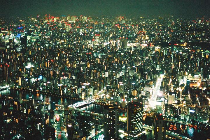 An aerial view shows a sprawling city at night, with a river and bridges visible.
