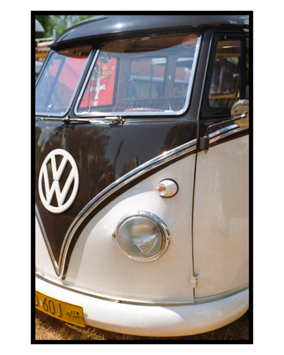 A close-up shot shows the front of a two-tone Volkswagen van with a yellow license plate.