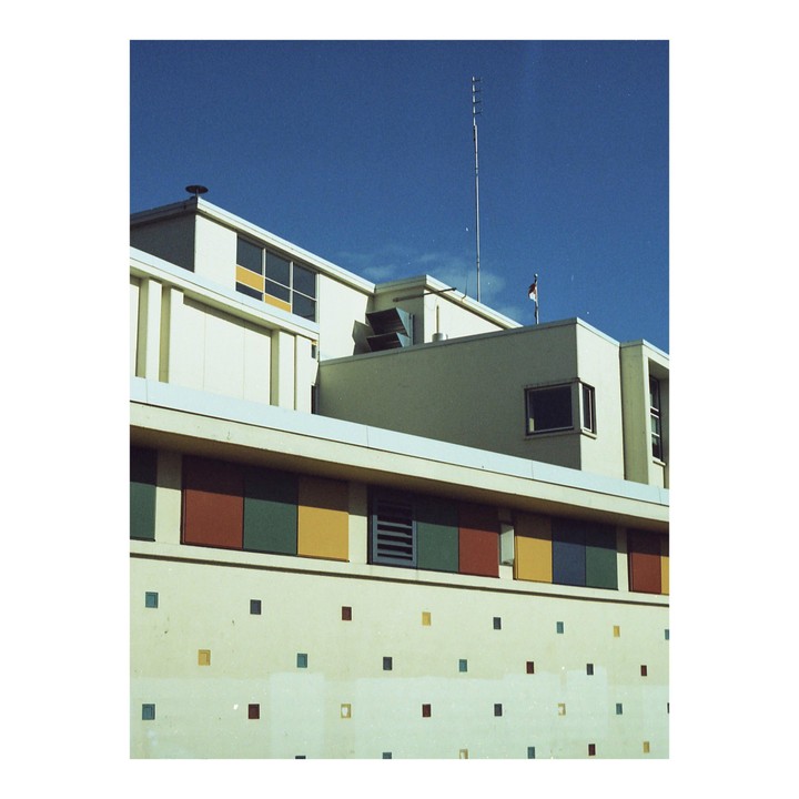 A building with colorful square decorations on its facade stands against a clear blue sky.