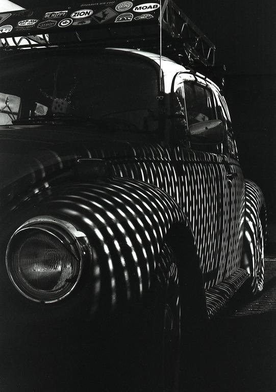 A Volkswagen Beetle is parked with striped shadows cast across its body.