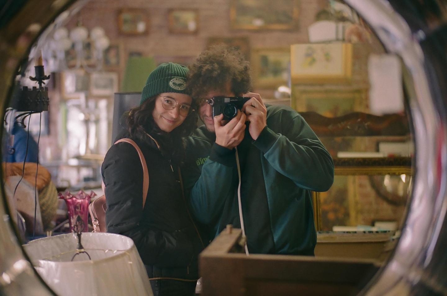 A couple takes a mirror self-portrait in an antique shop.