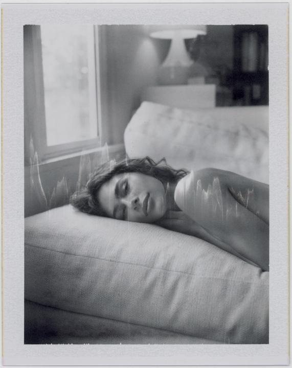 A woman with closed eyes rests her head on a pillow.