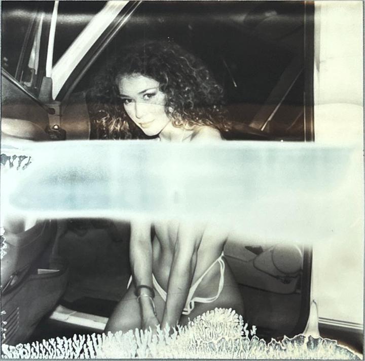 A woman with curly hair is sitting in a car.