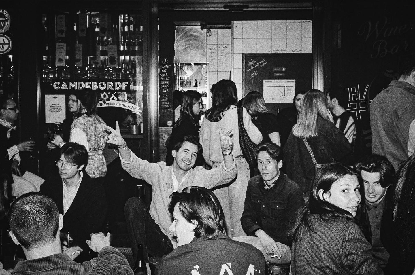 A group of people are gathered inside a bar at night.