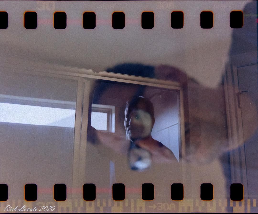 A man's face is visible through a window in a double exposure.