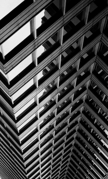 A black and white abstract architectural photograph shows the geometric patterns of a building's facade.